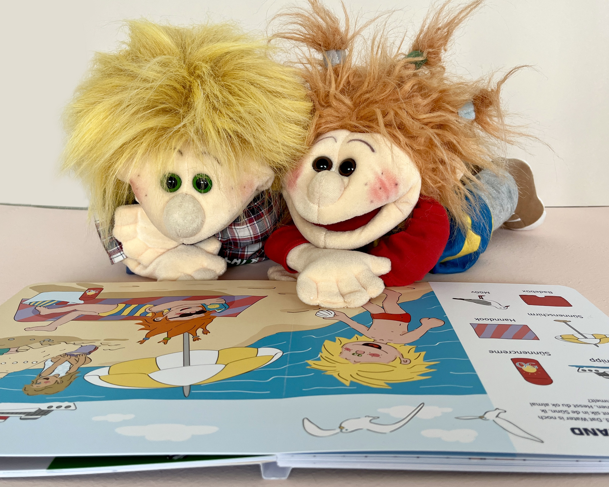 Die Sprachpuppen Hinnerk und Hanna schauen sich ihr plattdeutsches Kinderbuch an. Die Illustrationen stammen von Steffi Meyer von P-67 Industries.